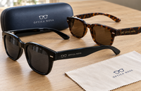 Gafas de sol con logotipo en las patillas junto a un estuche y una gamuza de la misma marca